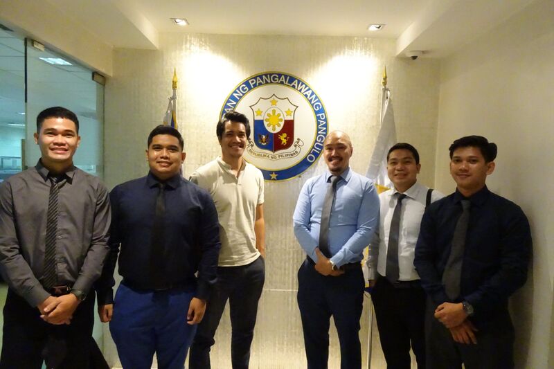 Project team posing in front of the Office of the Vice President seal